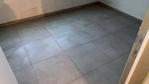 Lege kamer met grijze vierkante tegelvloer