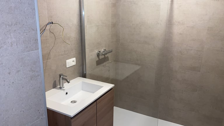 Modern bathroom with white sink, brown vanity, and glass shower enclosure