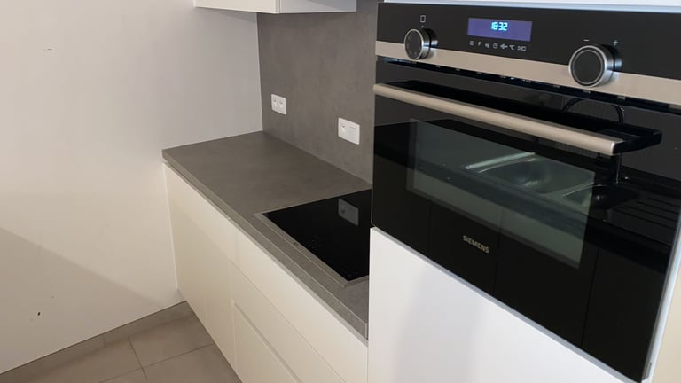 Modern kitchen with white cabinetry and built-in black electric oven