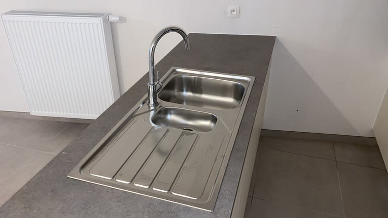 Stainless steel kitchen sink with black faucet on dark countertop